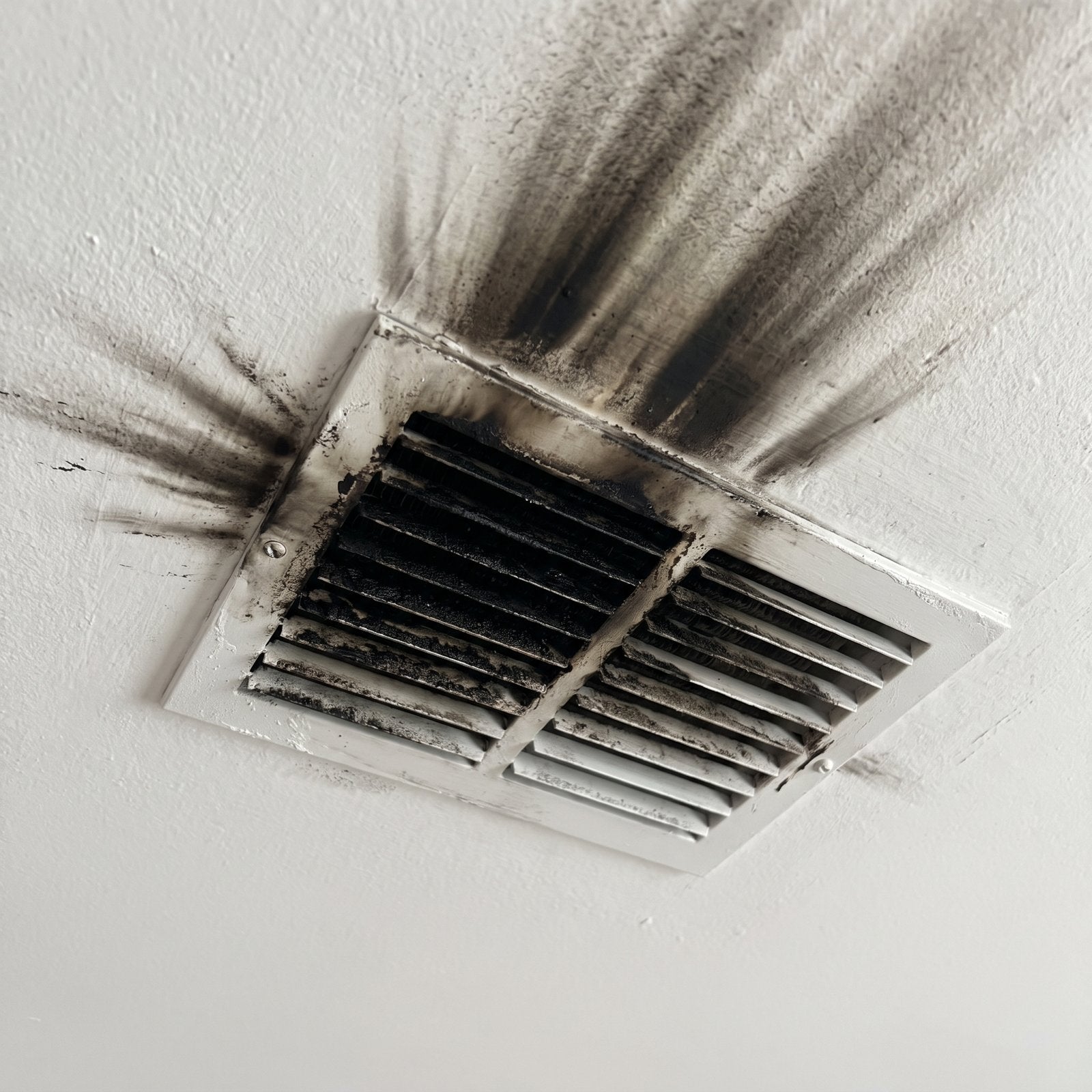 Soot and smoke staining fanning across a ceiling from an HVAC vent