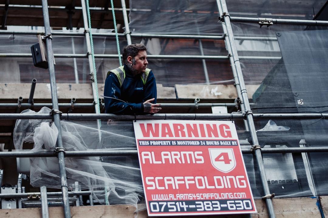 a man standing on a scaffold next to a warning sign